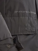 Campera de abrigo azul marino con capucha, cierre frontal con botones y cremallera, múltiples bolsillos y forro interior naranja.