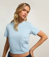 Remera tipo t-shirt de algodón, color beige claro, con cuello redondo y mangas cortas dobladas.