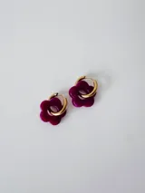 Aros de acero quirúrgico dorados con dije colgante en forma de flor de color fucsia.