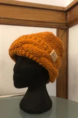 Gorro de lana color ocre, tejido a mano con punto trenzado y detalle de botón de madera cuadrado.