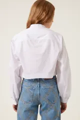 Camisa blanca corta de corte recto con cuello mao, mangas anchas con puños ajustados y aberturas trenzadas en las mangas. Incluye medalla de bronce con logo "TRS".