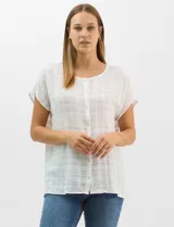 Blusa de corte fluido confeccionada en algodón con tejido texturizado de patrón a cuadros. Presenta mangas cortas caídas, escote redondo y cierre frontal con botones.