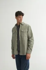 Sobrecamisa verde oliva de pana con cuello solapa, calce holgado, bolsillos con tapa en el pecho y botones personalizados.