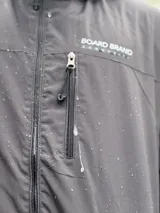 Campera impermeable azul marino con capucha ajustable y cierre frontal completo. Cuenta con bolsillos laterales y un bolsillo frontal con cierre en el pecho, además de puños elásticos.