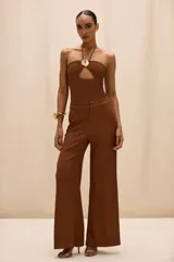 Pantalón de vestir color marrón con silueta amplia, corte recto y caída fluida. Presenta costuras verticales frontales que estilizan la figura y cierre clásico.