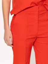 Pantalon de corte flare en color rojo, con tiro medio, cierre frontal con gancho y boton interno, y costuras verticales decorativas en el frente.