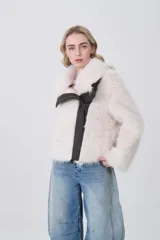 Tapado corto de piel sintética en color crema, con solapas amplias y cierre frontal asimétrico con detalles en cuero sintético oscuro.