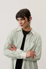 Camisa oversize a rayas color verde menta con cuello y puños en contraste de color blanco. Presenta cierre frontal con botones y un bolsillo aplicado en el pecho.