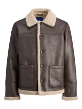 Campera de estilo western con exterior de cuero sintético marrón y forro interior de corderito (teddy) en color beige. Presenta cuello camisero, cierre frontal con botones y dos bolsillos frontales tipo parche.