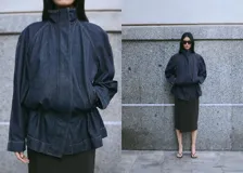 Parka oversize de tejido denim color azul oscuro, con cuello alto, mangas raglán largas, bolsillos laterales, cintura elástica y cierre frontal con botones ocultos.