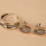Anillo de diseño ancho compuesto por una banda central de oro pulido flanqueada por dos bandas laterales de plata con textura arenada. El segundo anillo es una alianza de plata y oro con una hilera central de circonias engastadas.