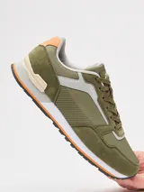 Championes urbanos Rusty modelo Nour, color verde oliva con detalles en gris, beige y naranja. Presentan una combinación de texturas en gamuza y material sintético, con suela de goma bicolor y cierre de cordones.