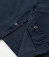 Camisa de manga corta color azul marino de corte boxy, con cuello inglés, cierre frontal de botones metálicos a presión y bolsillos cargo en el pecho.