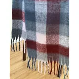 Bufanda rectangular de tejido grueso con diseño de cuadros en tonos azul, naranja, gris y beige, terminada con flecos en los extremos.