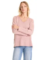 Buzo de tejido fino con acabado brillante de lurex, color beige, con escote en V, mangas largas con puños acanalados y ruedo con detalle de tejido acanalado más ancho.