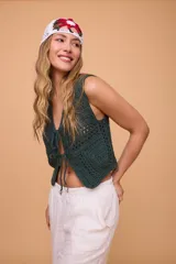 Chaleco corto tejido a mano en crochet, color celeste, con silueta ajustada, sin mangas y lazos en la delantera.