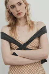 Vestido corto con escote en V y tirantes finos ajustables, confeccionado en tejido a cuadros beige y rojo. La falda es asimétrica y presenta un bajo con detalle de encaje.