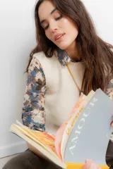 Chaleco tejido en lana merino, de color crudo, con cuello redondo y diseño clásico sin mangas.