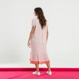 Vestido midi de corte recto, con estampado floral en tonos rosa y naranja sobre fondo crudo. Presenta cuello en V, mangas cortas y ruedo con volantes.