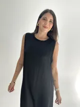 Vestido negro largo de tela satinada, sin mangas y con cuello redondo.