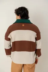 Buzo tejido de punto con diseño a rayas horizontales anchas en color marrón y beige. Presenta un cuello polo en color verde oscuro con cierre frontal de dos botones, mangas largas con puños elásticos y un corte boxy fit.