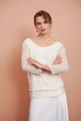 Blusa blanca con bordado de mostacillas y lentejuelas, escote redondo y manga larga.