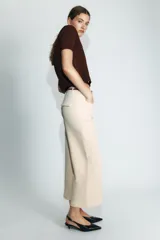 Pantalón culotte de tiro medio en color beige, con bolsillos de plastrón en el frente y costuras verticales. Incluye un cinturón trenzado fino en color marrón a contraste.
