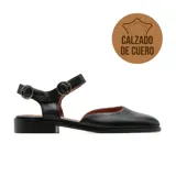 Sandalia baja de cuero negro, con puntera cuadrada, empeine cerrado y talón destalonado. Cuenta con tiras cruzadas en el empeine con hebillas metálicas ajustables.