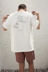 Remera blanca de algodón con estampado en la espalda con la frase "Follow the Waves" y dibujos de conchas marinas en color celeste.