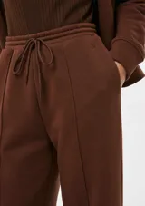 Pantalón de corte recto y holgado, color blanco, con cintura elástica y cordón ajustable. Presenta costuras verticales frontales que estilizan la silueta.