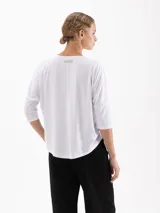 Remera de silueta relajada confeccionada en tela de punto suave. Presenta escote redondo, mangas 3/4, recorte estratégico en la espalda y tajos laterales que aportan movimiento y una caída fluida.