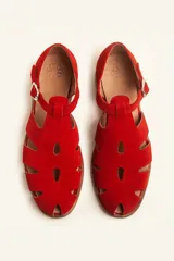 Sandalias de gamuza color marrón, estilo romano con diseño en T, tiras con aberturas laterales y cierre de hebilla metálica en el tobillo. Cuenta con tacón bajo de madera.