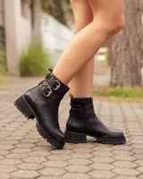 Botas cortas de cuero negro con suela track de goma y dos correas con hebillas metálicas ajustables en el tobillo.