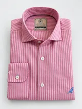 Camisa de lino Club House modelo Hudson, corte slim fit, de color rosado con rayas verticales blancas. Cuenta con cuello camisero, mangas largas, botones frontales y un pequeño bordado de un pájaro azul en la parte inferior.
