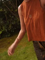 Chaleco de gamuza negro, sin mangas, con cuello redondo y diseño bordado de un sol en el pecho.