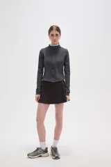 Campera deportiva de ajuste entallado, confeccionada en poliéster color gris oscuro. Presenta cuello alto, cierre frontal completo y mangas largas con aberturas para los pulgares.