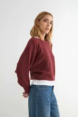 Sweater de punto negro, de corte holgado y diseño cropped, con cuello redondo y mangas largas.