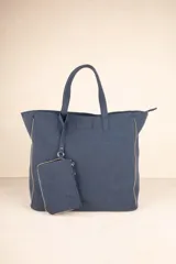 Bolso tipo tote bag azul con apliques de tachas plateadas en los laterales y monedero colgante con cierre.