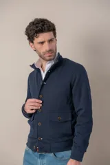 Campera azul marino tejida en algodón, con cuello mao, cierre frontal con botones, dos bolsillos de parche con botón en el frente y puños tejidos.