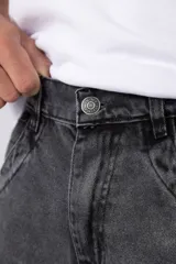 Jean de corte baggy y fit oversize, confeccionado en denim de algodón con lavado efecto gastado en color gris oscuro. Presenta costuras reforzadas en la zona de las rodillas y diseño de cinco bolsillos.