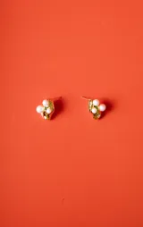 Par de aros dorados con textura irregular, adornados con tres perlas blancas y un pequeño cristal brillante.