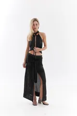 Top halter color bordó con tejido de lurex, escote con tiras cruzadas en el cuello y abertura frontal pronunciada con cordones ajustables.