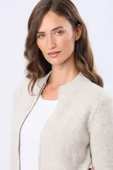 Campera tejida de abrigo color beige, con cierre frontal, cuello alto y bolsillos laterales.