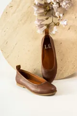 Zapato tipo ballerina color beige con correa al tobillo desmontable.