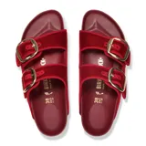 Sandalias Birkenstock modelo Arizona con diseño de doble tira en terciopelo color rojo óxido. Presenta hebillas grandes metálicas en tono dorado, plantilla anatómica de corcho y suela de goma negra.