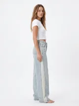 Jean wide leg de tiro alto en tono celeste claro, con franja lateral en contraste de color beige y corte amplio en las piernas.