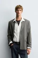 Blazer de corte boxy fit con estampado de espiga. Presenta cuello con solapas de muesca, cierre frontal de un botón, mangas largas con puños abotonados y bolsillos con solapa en la cadera.