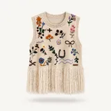 Chaleco tejido de punto color beige, sin mangas, con cuello redondo y diseño bordado a mano con motivos florales y detalles variados, con flecos largos en el ruedo.
