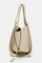 Bolso formato shopper de color beige, con detalle de pespuntes, cremalleras laterales con tiradores, doble asa y compartimento interior extraíble con cierre imantado.