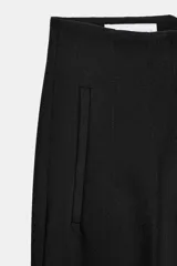 Pantalón tobillero de tiro alto y corte slim fit, con patrón de cuadros pequeños en tonos beige y negro. Presenta bolsillos delanteros de vivo y costuras marcadas en la parte delantera y trasera.